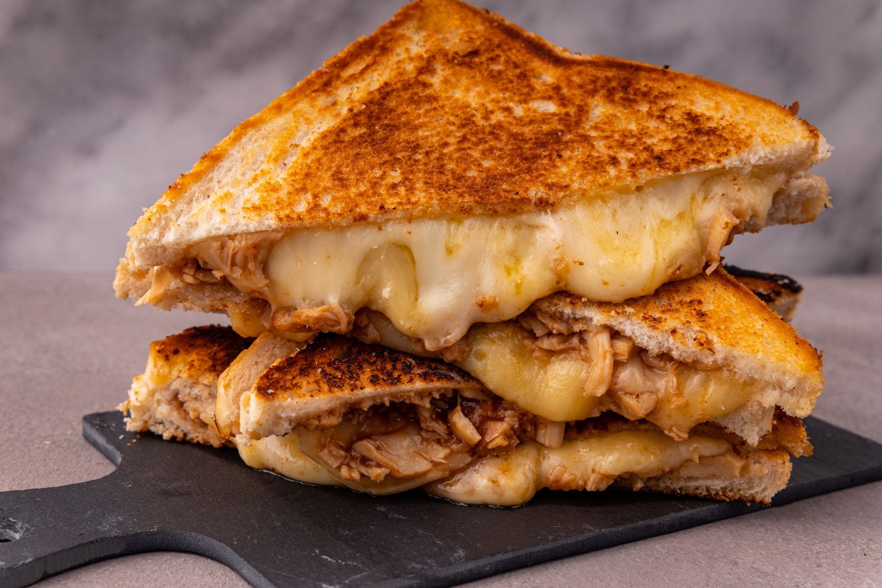 bbq pulled chicken grilled cheese sandwich on a serving board